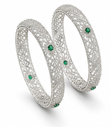 Pair of silver bangles with green gemstones on a white background