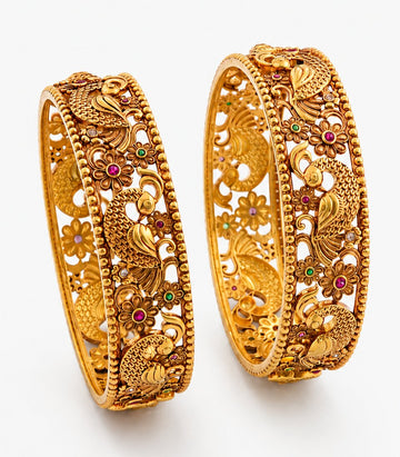 Two ornate gold bangles with intricate designs on a white background