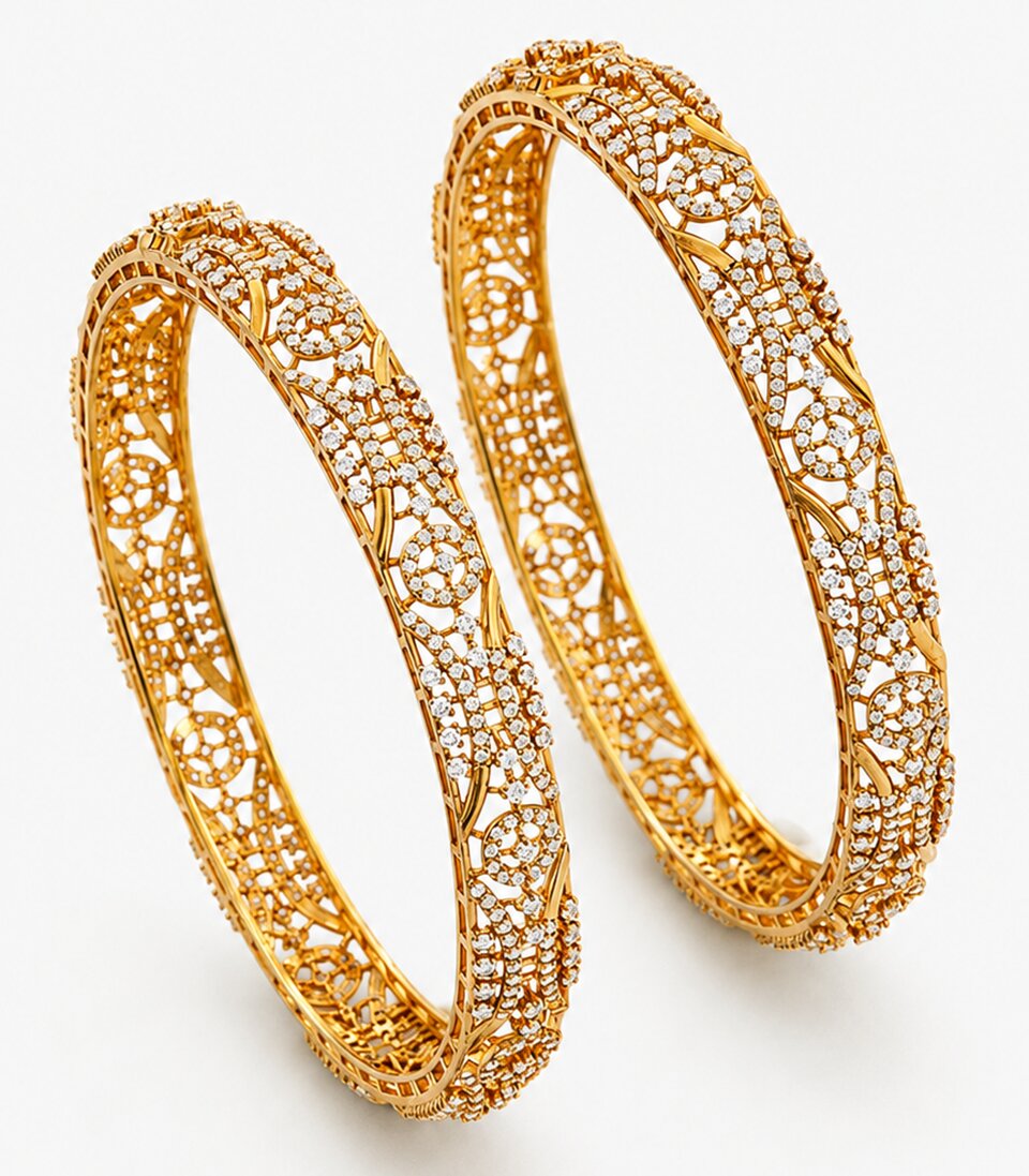 Pair of gold bangles with intricate designs on a white background