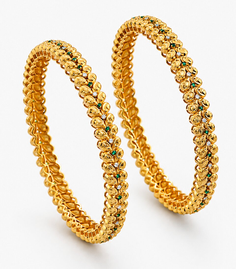 Two gold bangles with green stones on a white background