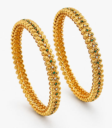 Two gold bangles with green stones on a white background