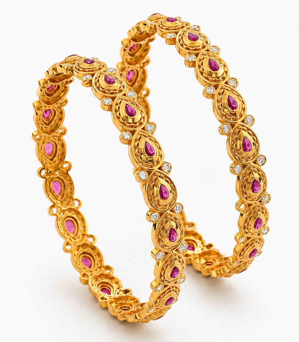 Pair of gold bangles with pink stones on a white background