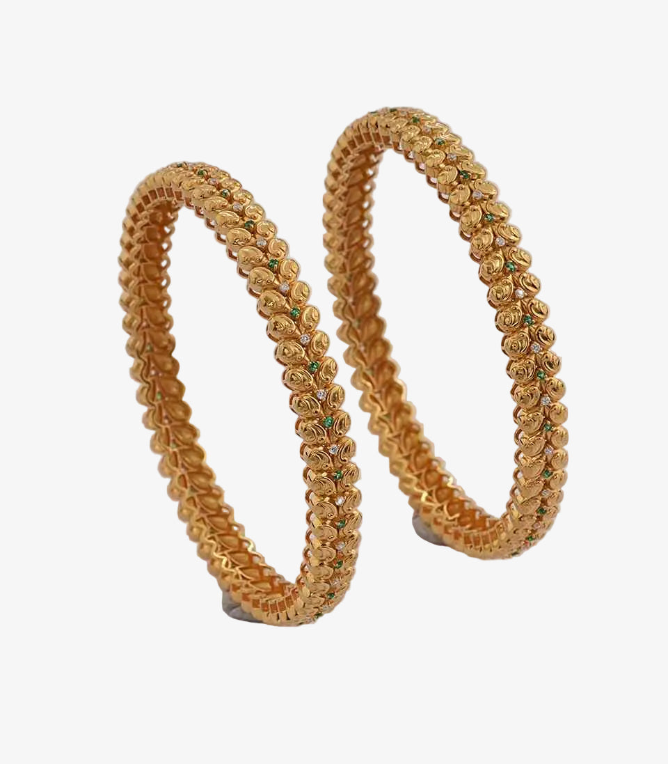 Pair of textured gold bangles with a repeating bead-like pattern, accented by small green and clear stones, displayed on a plain background.