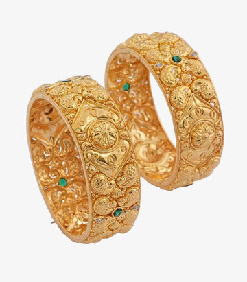 Kada-style bangles featuring intricate paisley and floral filigree work accented with emerald-toned gemstones.
