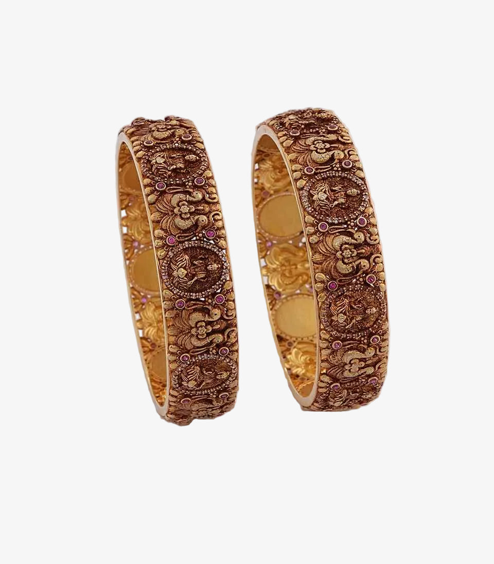 Pair of gold bangles with intricate designs on a white background