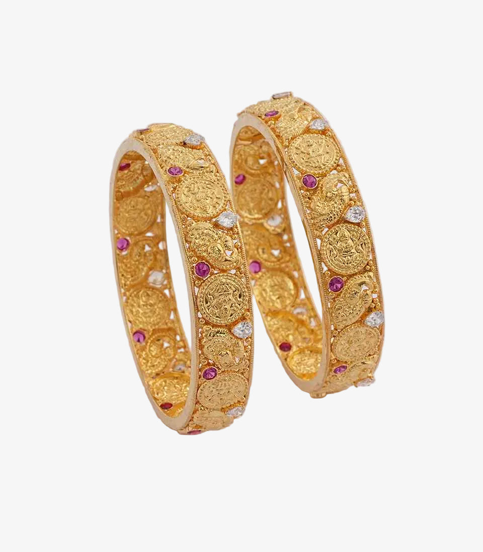 Pair of gold bangles with purple gemstones on a light background