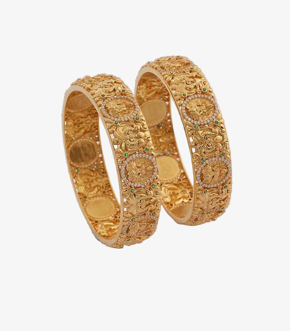 Pair of gold bangles with circular white design on a light background