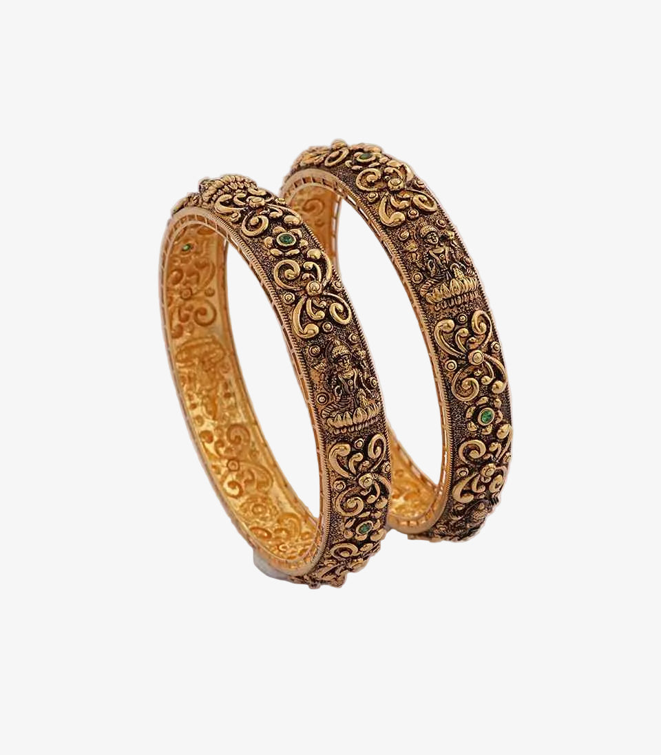 Pair of ornate gold bangles on a light  background