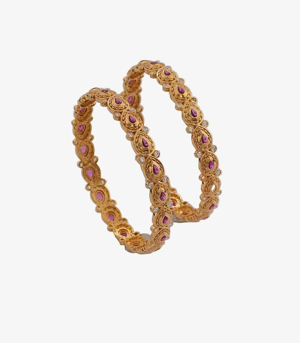 Graceful gold bangles featuring a sequence of teardrop-shaped ruby accents and small white stones set within circular, scalloped gold frames.