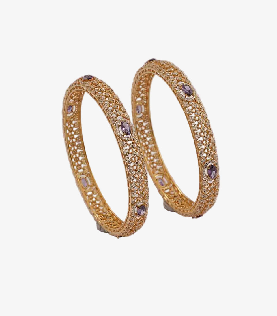 Pair of gold bangles with purple stones on a light background