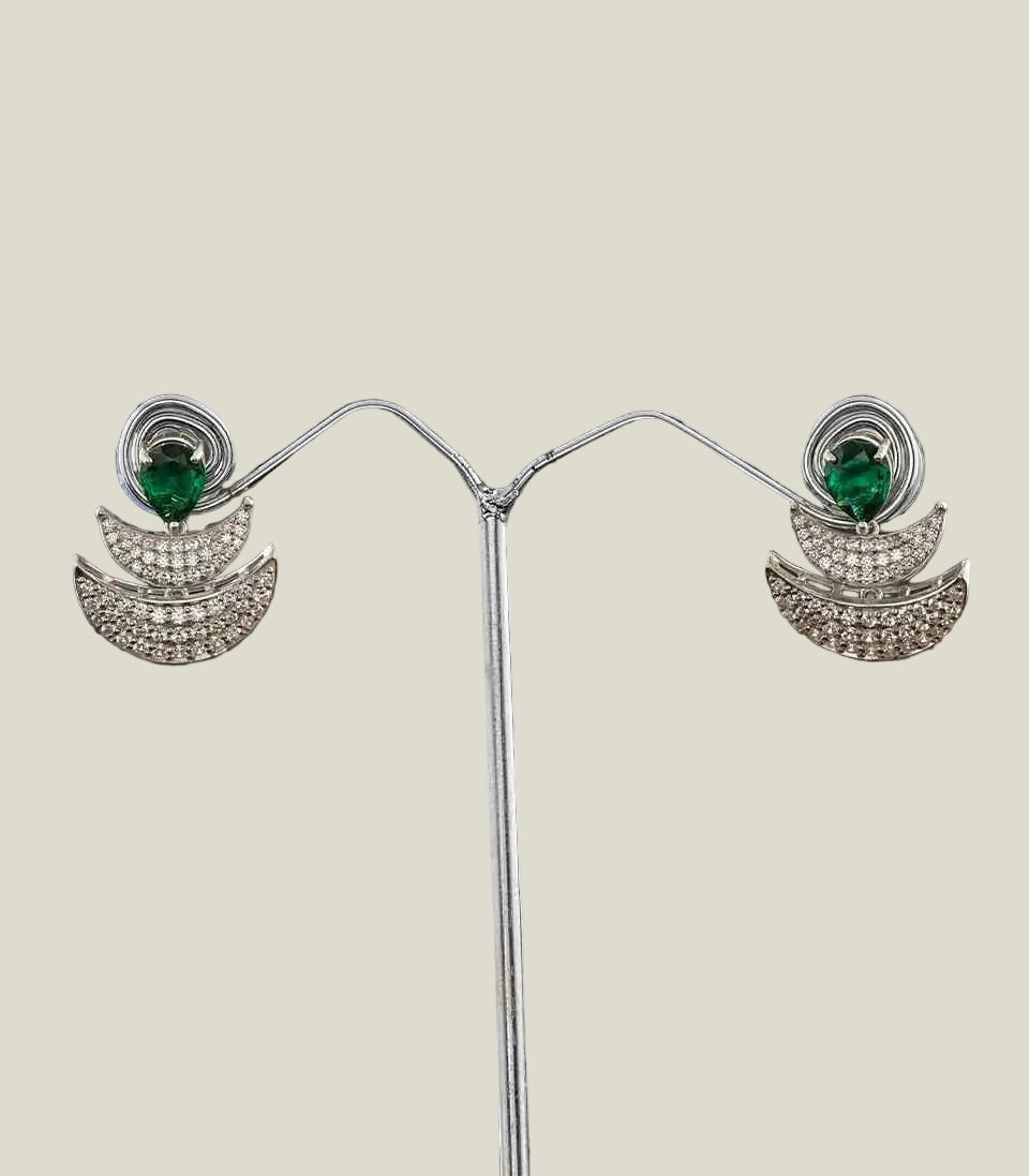 Pair of silver earrings with green gemstones on a dark background