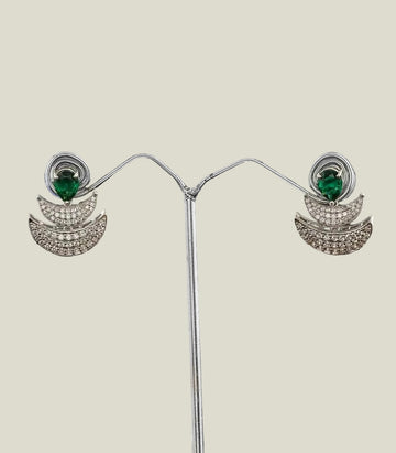 Pair of silver earrings with green gemstones on a dark background