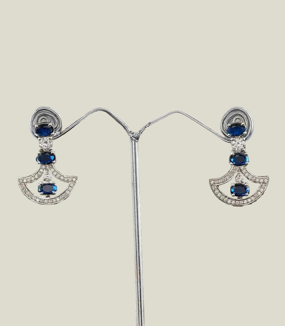 Pair of earrings with blue gemstones and silver setting on a dark background