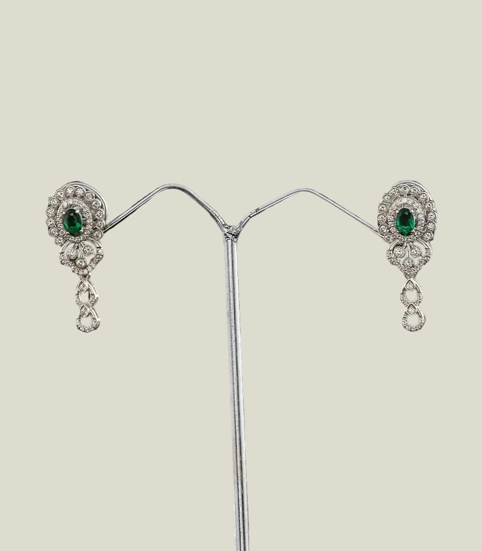 Pair of silver earrings with green gemstones on a dark background