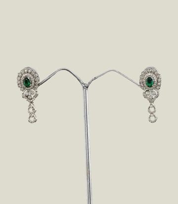Pair of silver earrings with green gemstones on a dark background