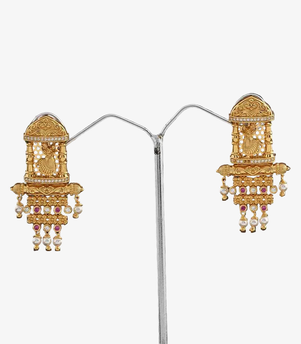 Pair Of Gold Earrings With Intricate Temple and Dancing Girl Designs on a dark background
