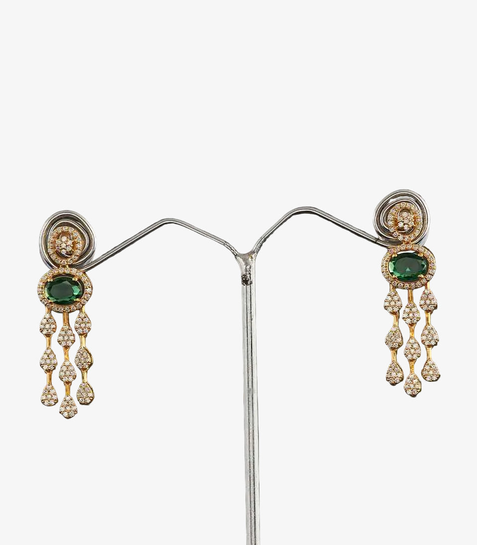 Pair of earrings with emerald and diamond accents on a dark background