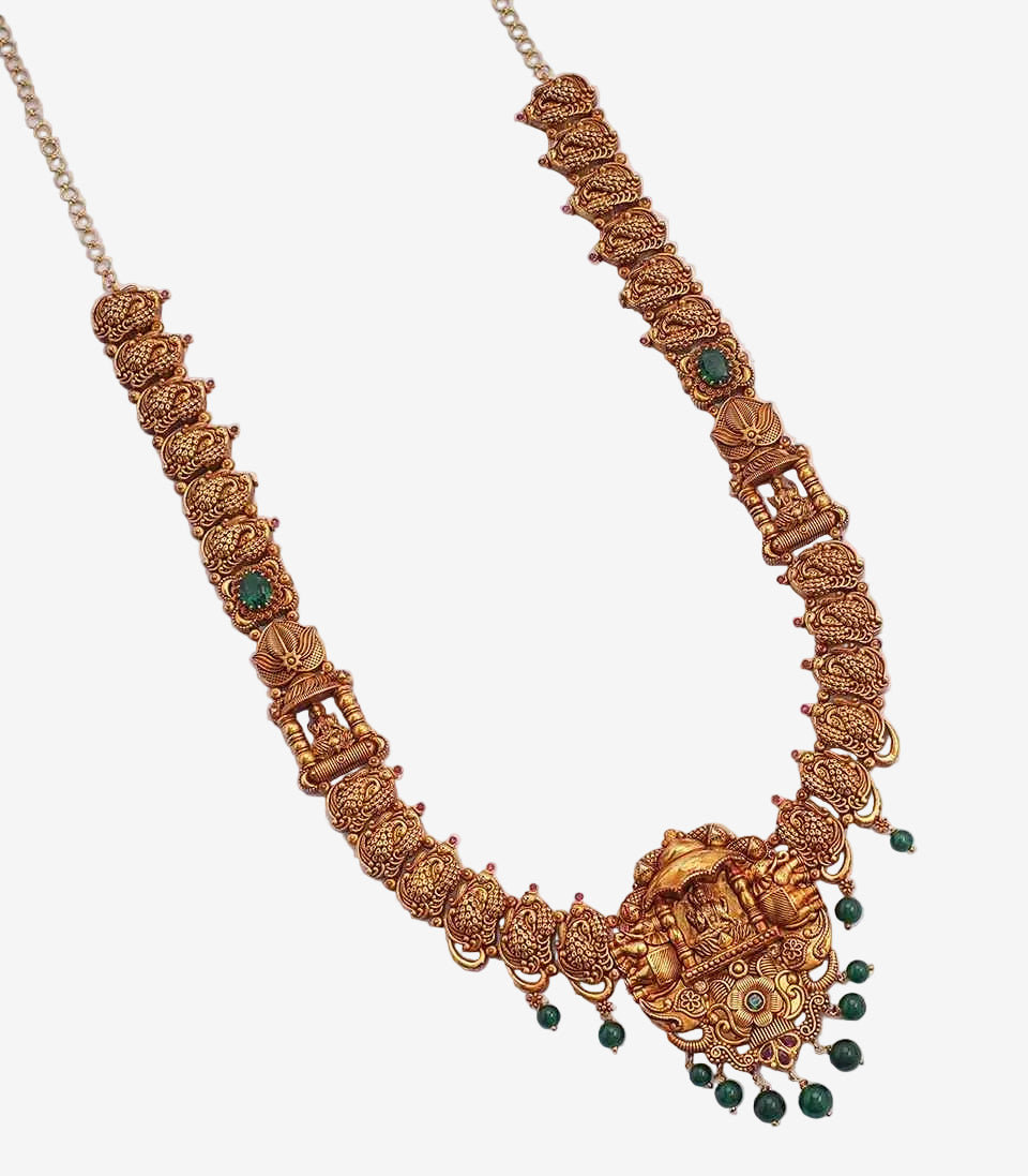 Ornate gold necklace with green gemstones on a light gray background