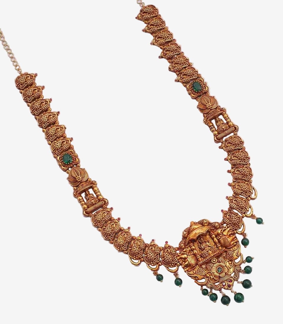 Ornate gold necklace with green beads on a white background