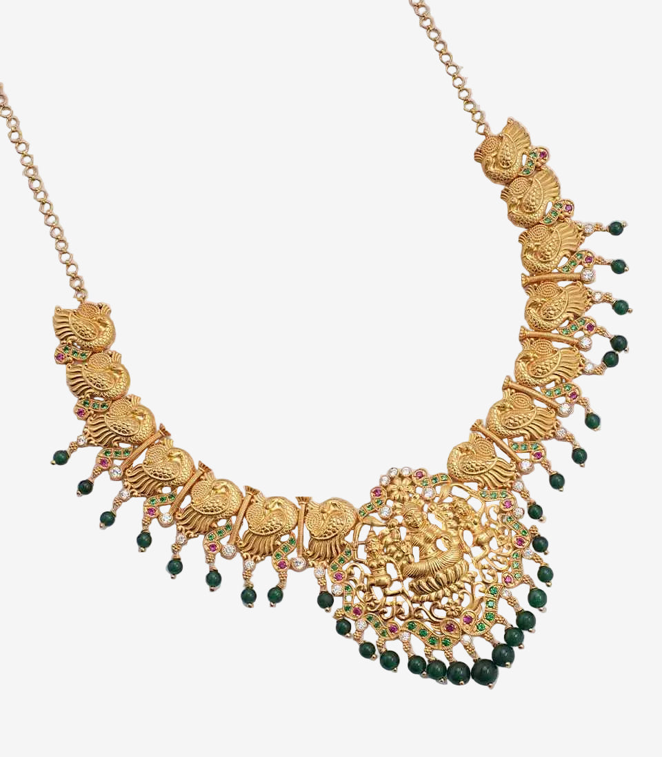 Gold necklace with green beads on a light gray background