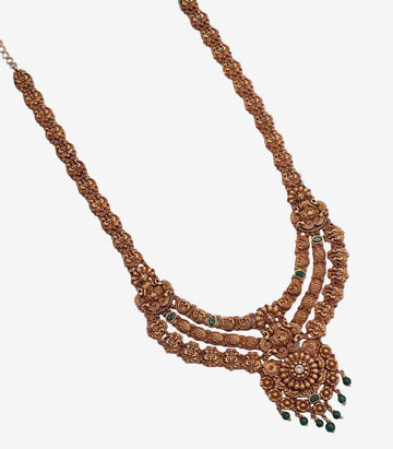 Decorative gold necklace with green stones on a white background