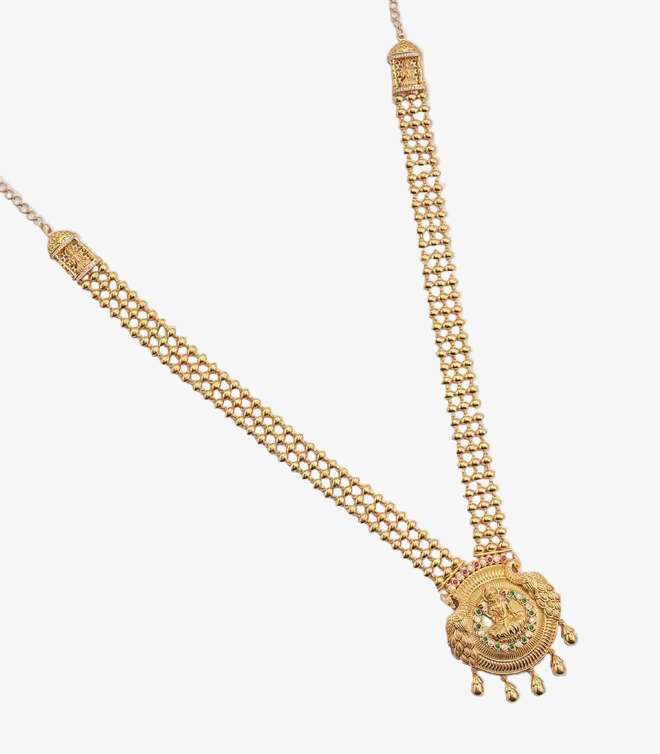 A long gold necklace with a triple-strand beaded chain, featuring rectangular side accents and a circular medallion pendant depicting a deity, framed by green and red stones with small gold droplets at the base.