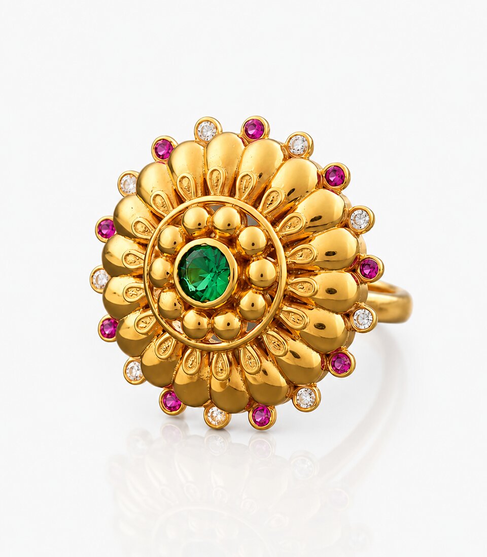 Gold ring with green gemstone and red and white stones on a light gray background