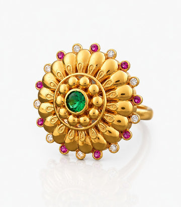 Gold ring with green gemstone and red and white stones on a light gray background