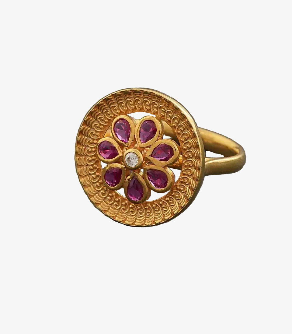 Gold ring with floral design and red gemstones on a gray background