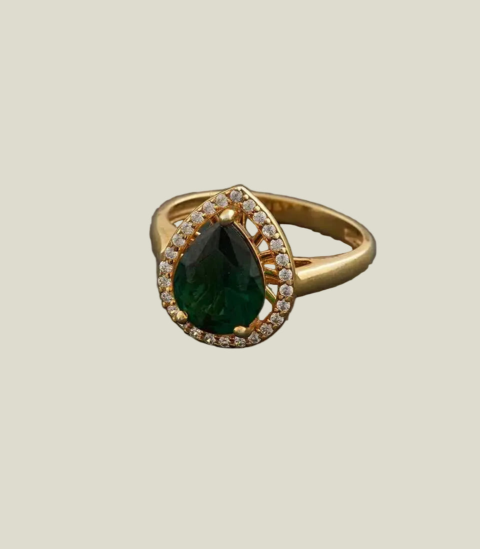 Gold ring with a green gemstone on a gray background
