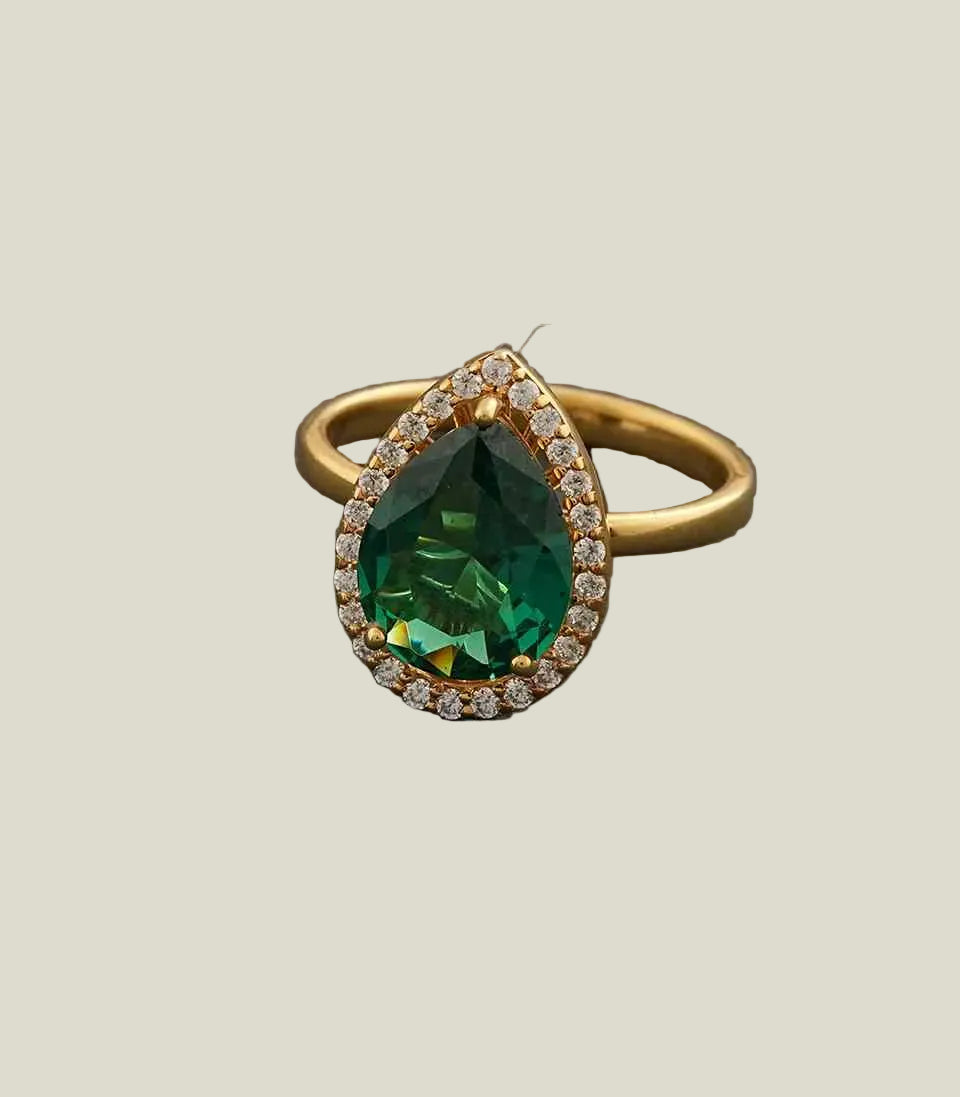 Gold ring with a green gemstone on a gray background