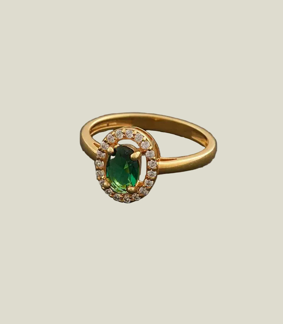 Gold ring with a green gemstone on a gray background
