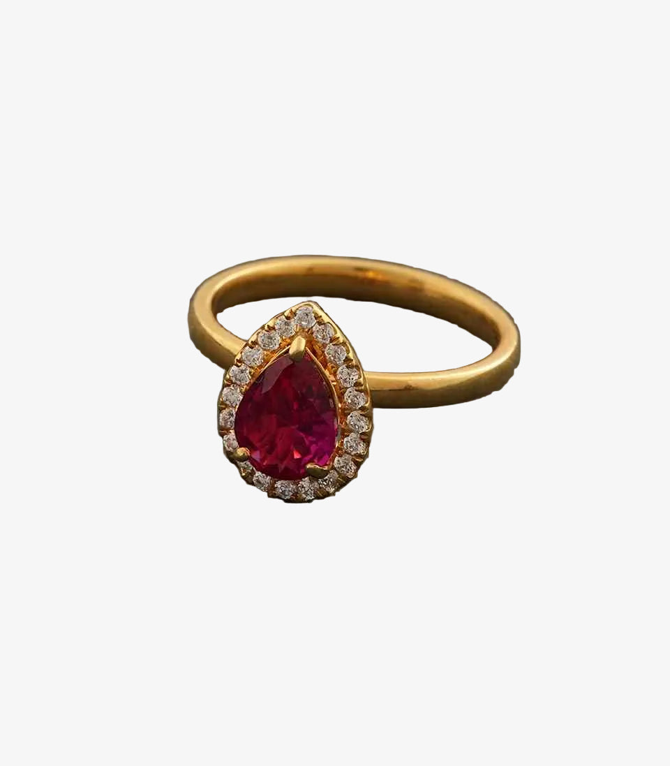 Gold ring with a red gemstone on a gray background