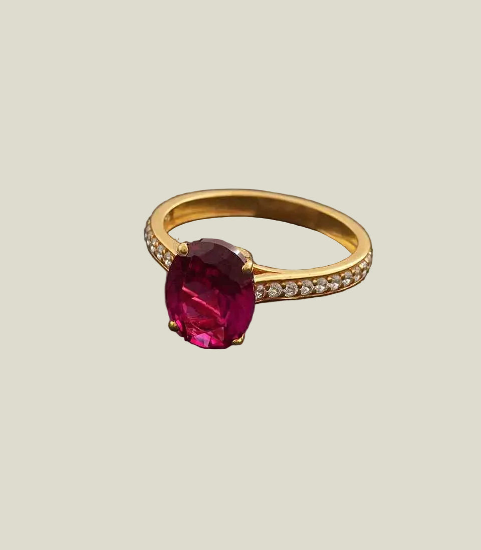 Gold ring with a large red gemstone on a dark gray background