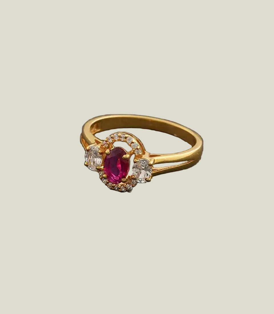 Gold ring with a red gemstone and diamonds on a gray background