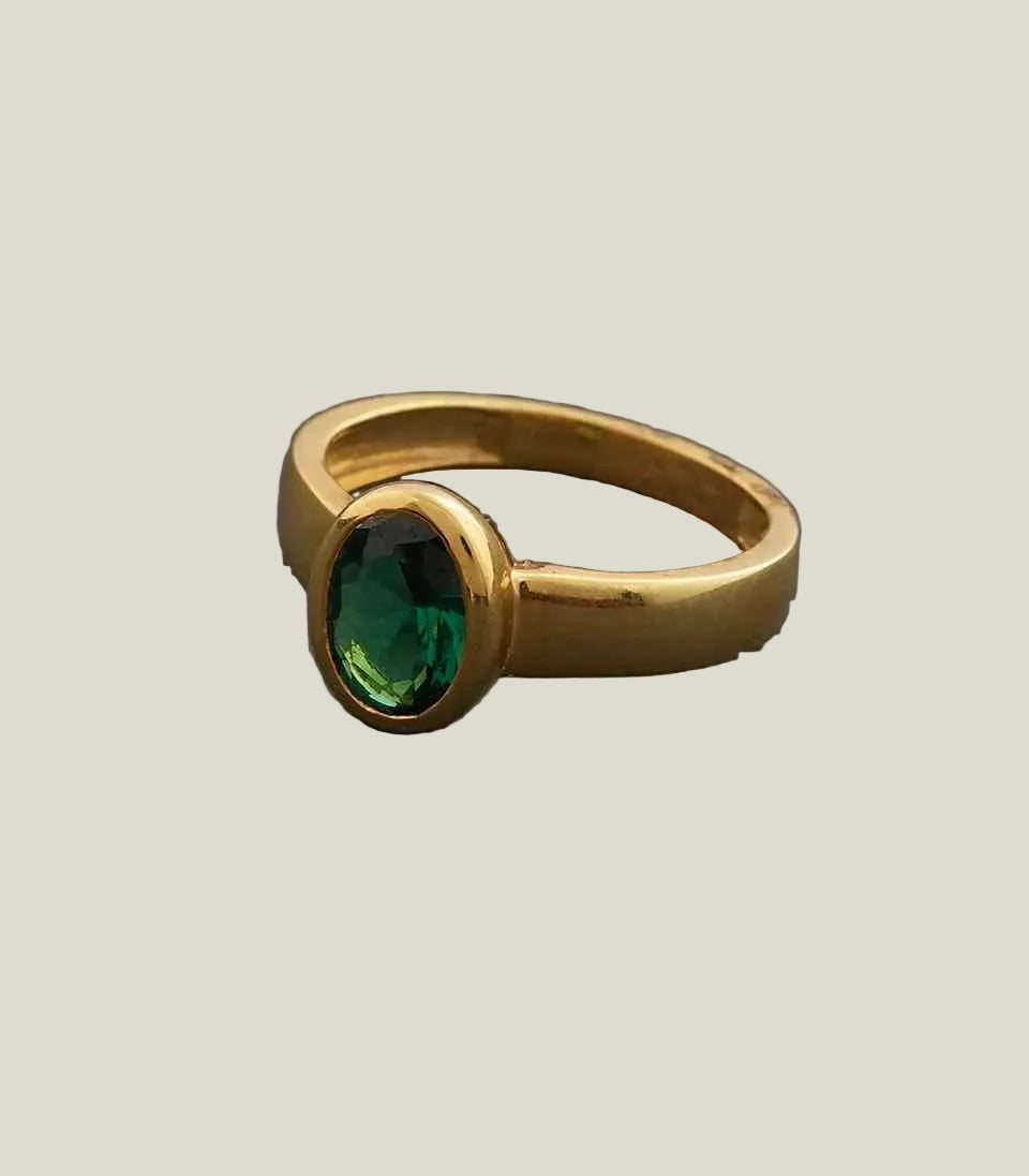 Gold ring with a green gemstone on a gray background