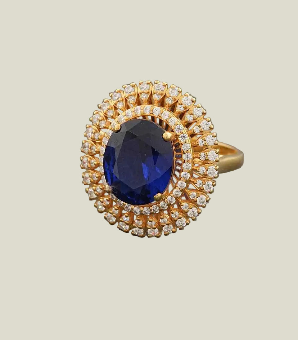 Gold ring with a blue gemstone and diamond accents on a gray background