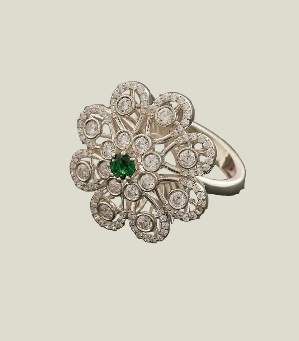 ring with floral design and green gemstone on a dark gray background