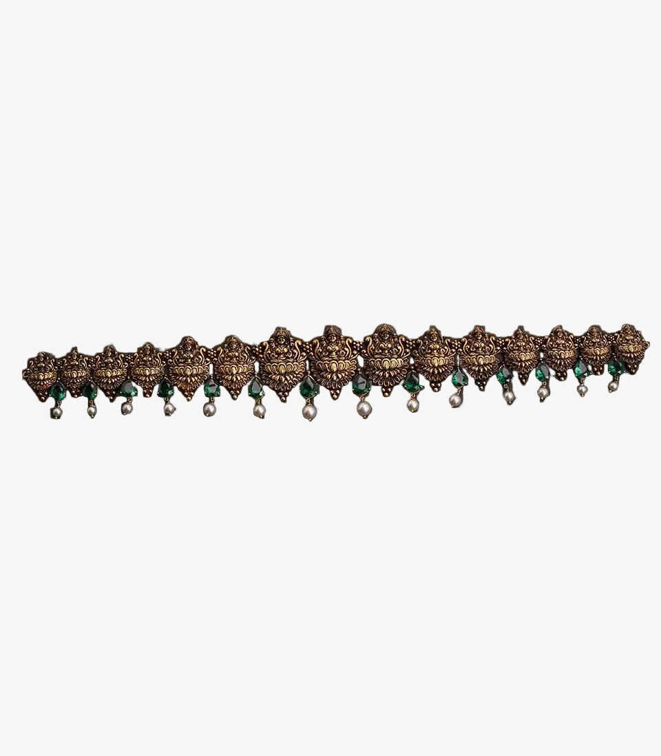 This is a traditional antique-finish Temple Jewelry Vaddanam (waist belt) featuring intricate goddess motifs, green stones, and pearl droplets.